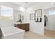 Bright bathroom featuring a freestanding tub, vanity with sink, and a large mirror enhancing the natural light and space at 7441 W Buckhorn Trl, Peoria, AZ 85383