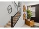 Modern staircase with black railing, tan carpet, and stylish wall decorations, complemented by a comfortable mustard chair and plant at 7441 W Buckhorn Trl, Peoria, AZ 85383