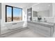 Bright bathroom featuring dual sinks, soaking tub by the window, and a heated towel rack at 1040 E Osborn Rd # 1004, Phoenix, AZ 85014