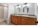 Bathroom featuring double sinks with granite countertops and warm wood cabinets next to bathtub and toilet at 1051 S Dobson Rd # 137, Mesa, AZ 85202