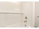Clean white tiled bathtub and shower combo with sleek fixtures and a built-in shelf, offering comfort at 11615 W Beck Ave, Youngtown, AZ 85363
