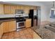 Well-equipped kitchen with stainless steel appliances, wood cabinets, and tile flooring for easy maintenance at 12914 W Wilshire Dr, Avondale, AZ 85392