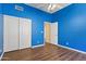 Bedroom with wood floors, ceiling fan, closet and a bright blue accent wall at 1313 W Straford Ave, Gilbert, AZ 85233