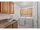 Functional laundry room featuring a sink, granite counters, storage cabinets, washer, and dryer at 1313 W Straford Ave, Gilbert, AZ 85233