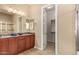 Bathroom with double sinks, granite counters, and an open doorway to a walk-in closet at 15313 S 180Th Ave, Goodyear, AZ 85338