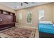 Bedroom featuring a blue bedspread, built-in desk, tan walls, tile floor, a ceiling fan, and windows at 15313 S 180Th Ave, Goodyear, AZ 85338