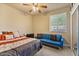 Inviting bedroom with a ceiling fan, comfortable bed, and blue sofa next to window for relaxing at 15442 W Sells Dr, Goodyear, AZ 85395