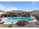 Private pool with rock feature surrounded by desert landscaping and mature trees at 15442 W Sells Dr, Goodyear, AZ 85395