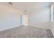 Light-filled bedroom with plush carpeting, neutral walls and an open doorway to a bathroom at 15564 W Williams St, Goodyear, AZ 85338