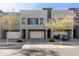 Modern townhome exterior featuring three garages with gray stucco and desert landscaping at 25318 N 19Th Dr, Phoenix, AZ 85085