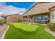 An alluring backyard featuring a well-manicured lawn, synthetic putting green, and covered patio seating area at 41553 W Springtime Rd, Maricopa, AZ 85138