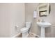 Neutral powder room featuring a pedestal sink, round mirror, and wood-look tile flooring at 41553 W Springtime Rd, Maricopa, AZ 85138