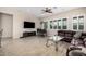 Spacious living room with natural light, featuring tile floors, a modern ceiling fan, and a comfortable brown leather sofa at 41553 W Springtime Rd, Maricopa, AZ 85138