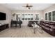 Spacious living room with natural light, featuring tile floors, a modern ceiling fan, and a comfortable brown leather sofa at 41553 W Springtime Rd, Maricopa, AZ 85138
