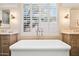 Elegant bathroom with a standalone tub, wood cabinets, and plantation shutters at 42211 N Long Cove Way, Anthem, AZ 85086