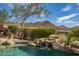 Beautiful pool featuring rock waterfall and desert landscaping, with mountain views in the background at 42211 N Long Cove Way, Anthem, AZ 85086