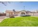 Expansive backyard featuring a lush green lawn, stone fireplace, and view of the home's exterior and pool at 6414 W Monterey Pl, Chandler, AZ 85226