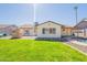 Lush backyard with a green lawn, stone pathway, cozy fireplace, and view of the home's exterior at 6414 W Monterey Pl, Chandler, AZ 85226