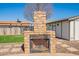 Outdoor stone fireplace with metal grate is the focal point of backyard on a stone patio and green lawn at 6414 W Monterey Pl, Chandler, AZ 85226