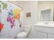 Bright bathroom features a world map shower curtain, white vanity, toilet, and wall art at 6513 W Latona Rd, Laveen, AZ 85339