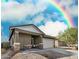 Charming single-story home with a two-car garage, stone accents, and a rainbow in the sky at 6513 W Latona Rd, Laveen, AZ 85339