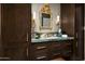 Luxurious bathroom featuring a marble countertop, custom dark wood cabinets, and a decorative gold mirror at 8541 N Farview Dr, Scottsdale, AZ 85258