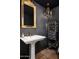 Stylish powder room featuring a pedestal sink, ornate gold mirror, dark wallpaper, and decorative display cabinet at 8541 N Farview Dr, Scottsdale, AZ 85258