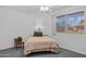 A simplistic bedroom with a queen bed, wooden bedside table, and carpeted flooring at 10408 N 105Th Ave, Sun City, AZ 85351