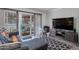 Cozy living room featuring a dark gray sofa, modern television, and sliding glass door at 10408 N 105Th Ave, Sun City, AZ 85351