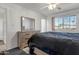 Primary bedroom featuring a dresser with mirror and a sunlit window, creating a serene atmosphere at 10408 N 105Th Ave, Sun City, AZ 85351
