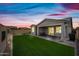 Backyard with vibrant sunset, green grass, and a covered patio, perfect for evening relaxation and entertainment at 10726 E Tallahassee Ave, Mesa, AZ 85212