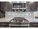Close up of kitchen stove and microwave set amongst dark wooden cabinets with stylish backsplash at 10726 E Tallahassee Ave, Mesa, AZ 85212