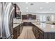 Open kitchen with stainless steel appliances, large island, dark wood cabinetry, and decorative tile backsplash at 10726 E Tallahassee Ave, Mesa, AZ 85212