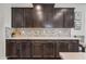 Kitchen countertops and dark wood cabinets with decorative backsplash, plants, and other decor elements at 10726 E Tallahassee Ave, Mesa, AZ 85212