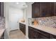 Butlers pantry with dark cabinets, quartz countertops, and decorative backsplash adjacent to a white entry door at 10726 E Tallahassee Ave, Mesa, AZ 85212