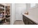 Walk-in pantry with custom shelving, quartz countertops, dark cabinets and direct access to the entry door at 10726 E Tallahassee Ave, Mesa, AZ 85212