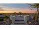 Beautiful backyard with a circular fire pit, stone landscaping, and an attractive desert sunset at 14562 W Georgia Ave, Litchfield Park, AZ 85340