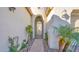 Charming courtyard entrance with lush greenery, pavers, and an ornate arched doorway at 14562 W Georgia Ave, Litchfield Park, AZ 85340