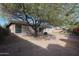 Private backyard featuring mature trees, brick patio, and desert landscaping at 18457 W Ivy Ln, Surprise, AZ 85388