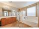 A bathroom featuring a soaking tub, glass shower, and a double sink vanity at 18457 W Ivy Ln, Surprise, AZ 85388