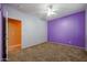 Bedroom with carpet flooring, purple accent wall, and ceiling fan at 18457 W Ivy Ln, Surprise, AZ 85388
