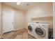 Bright laundry room features tile flooring, washer, dryer and overhead shelving at 18457 W Ivy Ln, Surprise, AZ 85388
