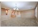 Spacious living room featuring neutral walls, carpet flooring, and a decorative chandelier at 18457 W Ivy Ln, Surprise, AZ 85388