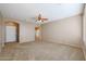 Neutral living room featuring plush carpeting, a ceiling fan, and an arched doorway at 18457 W Ivy Ln, Surprise, AZ 85388