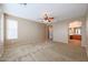 Carpeted main bedroom features a ceiling fan and leads into the Primary bath at 18457 W Ivy Ln, Surprise, AZ 85388