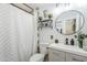 Bathroom featuring a round mirror, single sink vanity, open shelving with decor, and a patterned shower curtain at 1926 W Holly St, Phoenix, AZ 85009