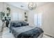 Bedroom with gray upholstered bed, matching bedding, plantation shutters, modern light fixture and decorative hanging plants at 1926 W Holly St, Phoenix, AZ 85009