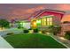 Beautiful single-story home with lush landscaping and brick accents, illuminated by decorative lights at twilight at 20729 E Canary Way, Queen Creek, AZ 85142