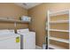 Functional laundry room with modern washer, dryer, and open storage shelving at 21630 N 30Th Ln, Phoenix, AZ 85027