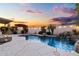Lush backyard featuring a stunning pool with a waterfall, a cozy seating area, and a picturesque sunset backdrop at 21630 N 30Th Ln, Phoenix, AZ 85027